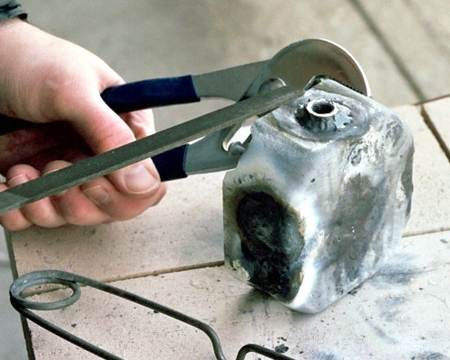 Smoothing up the exhaust port with large half-round file (c) 2004 Larry Cottrill